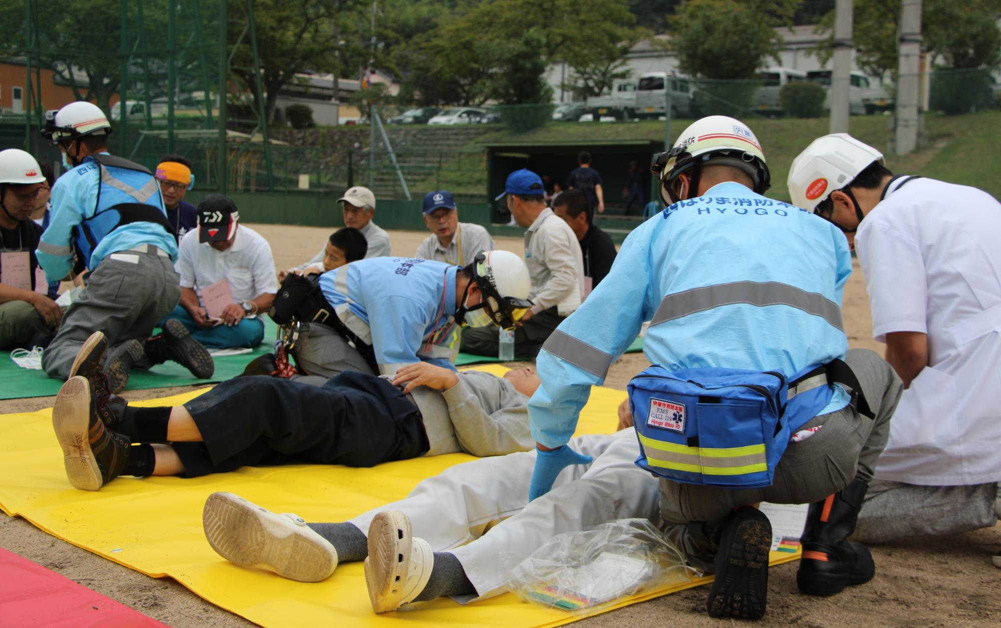 宍粟市総合防災訓練で患者役の市民が救急隊員と医師のトリアージを受ける写真