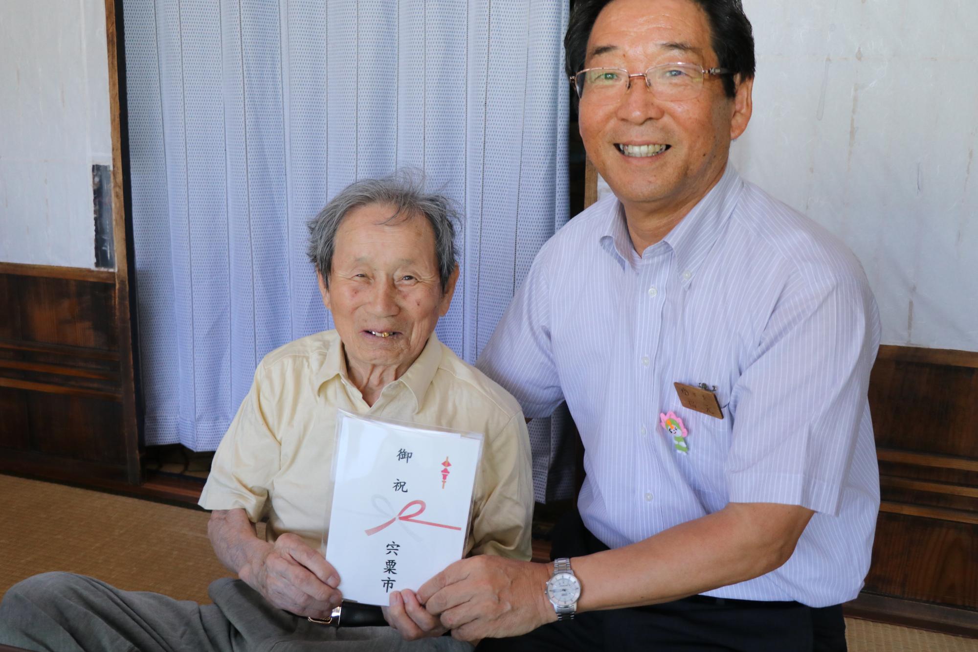 最高齢夫婦の森脇高一さんに記念品を贈る市長の写真