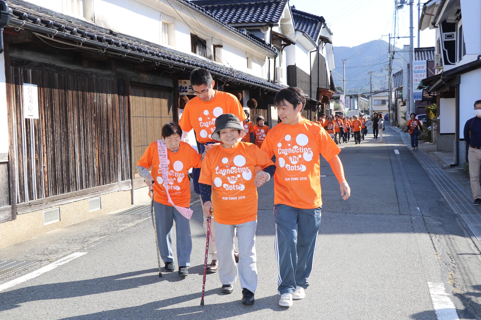 オレンジ色のシャツを着て走る参加者と支援者の写真