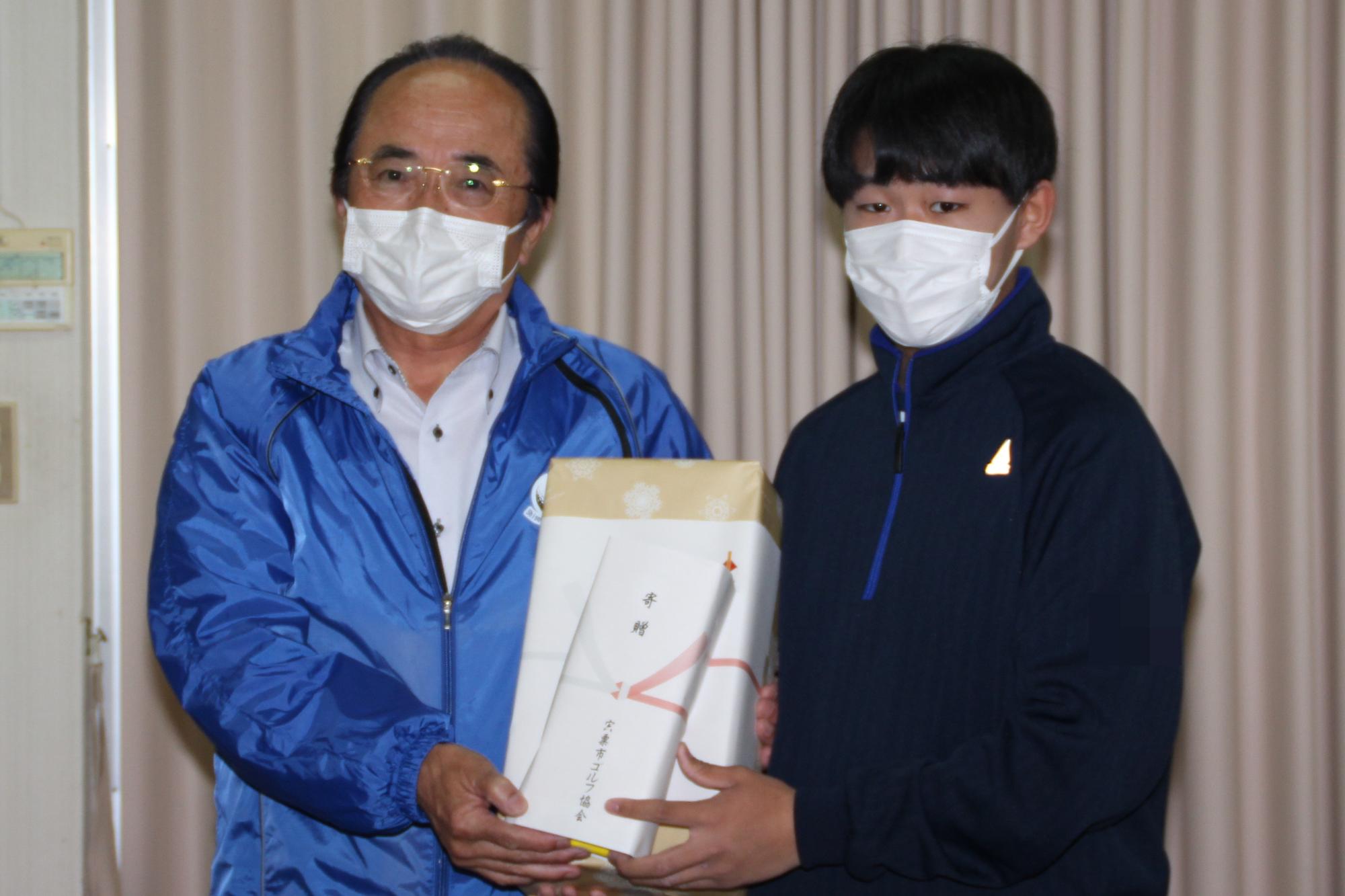 千草カントリークラブで市ゴルフ協会の会長からシューズとグローブを受け取る千種高校の生徒