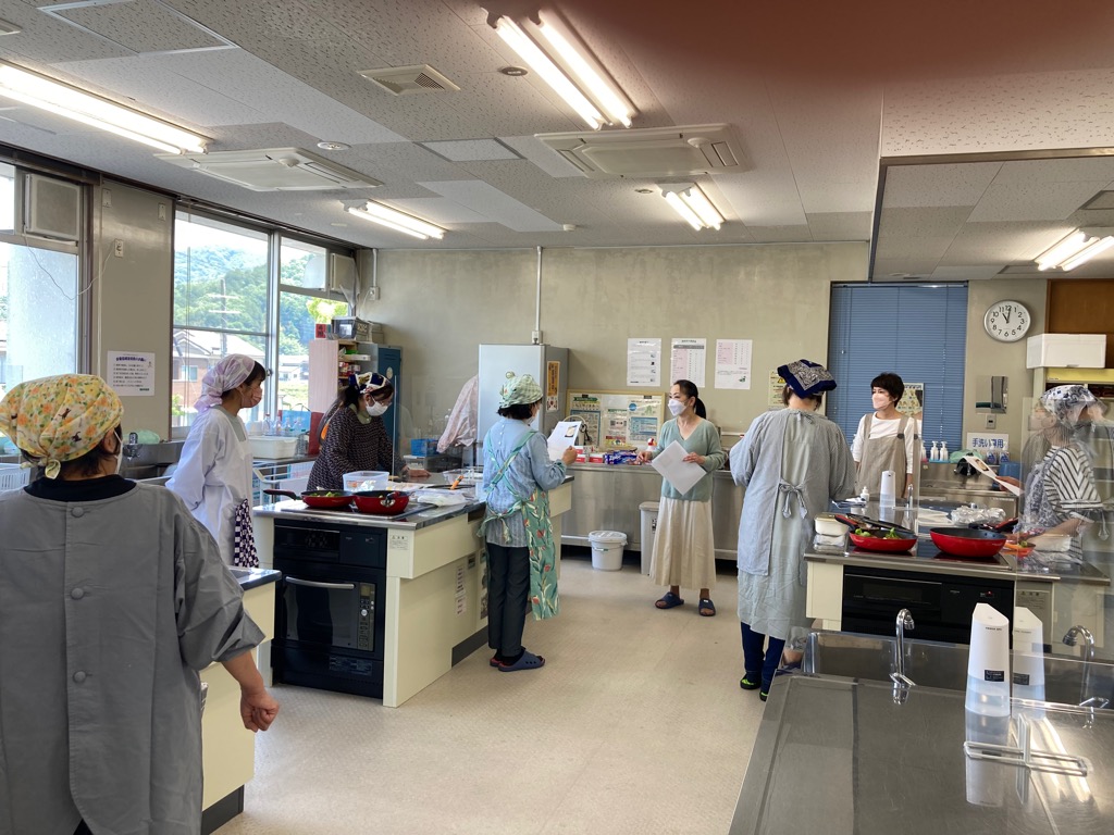 調理室で資料を手に講師の話を参加者が聞いている写真