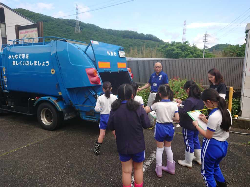 屋外でゴミ収集車を児童らが見学している写真