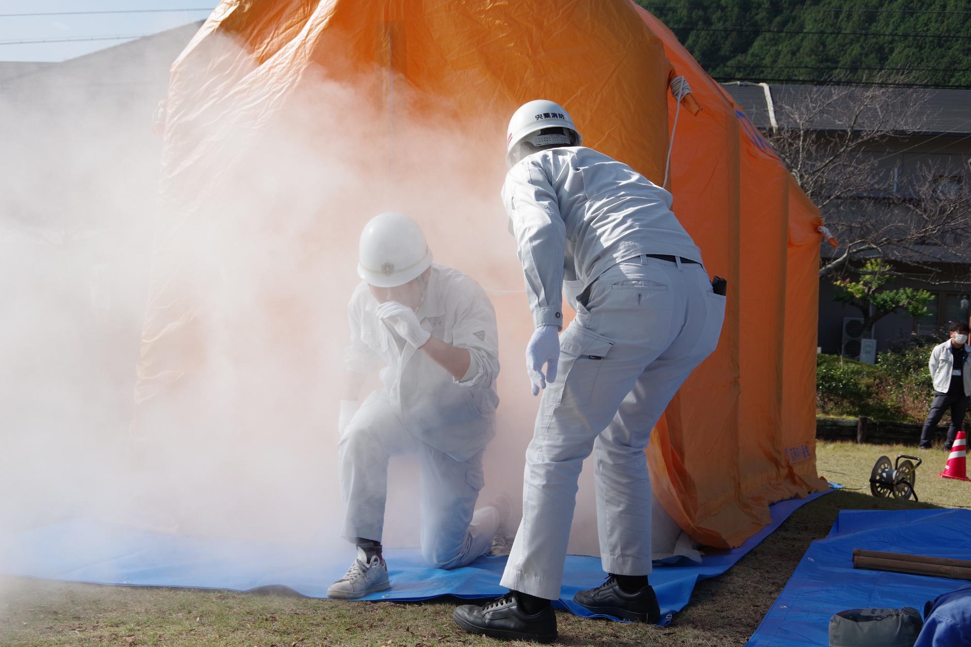 参加者らが煙が出るハウスの中で火事の現場を体験している写真