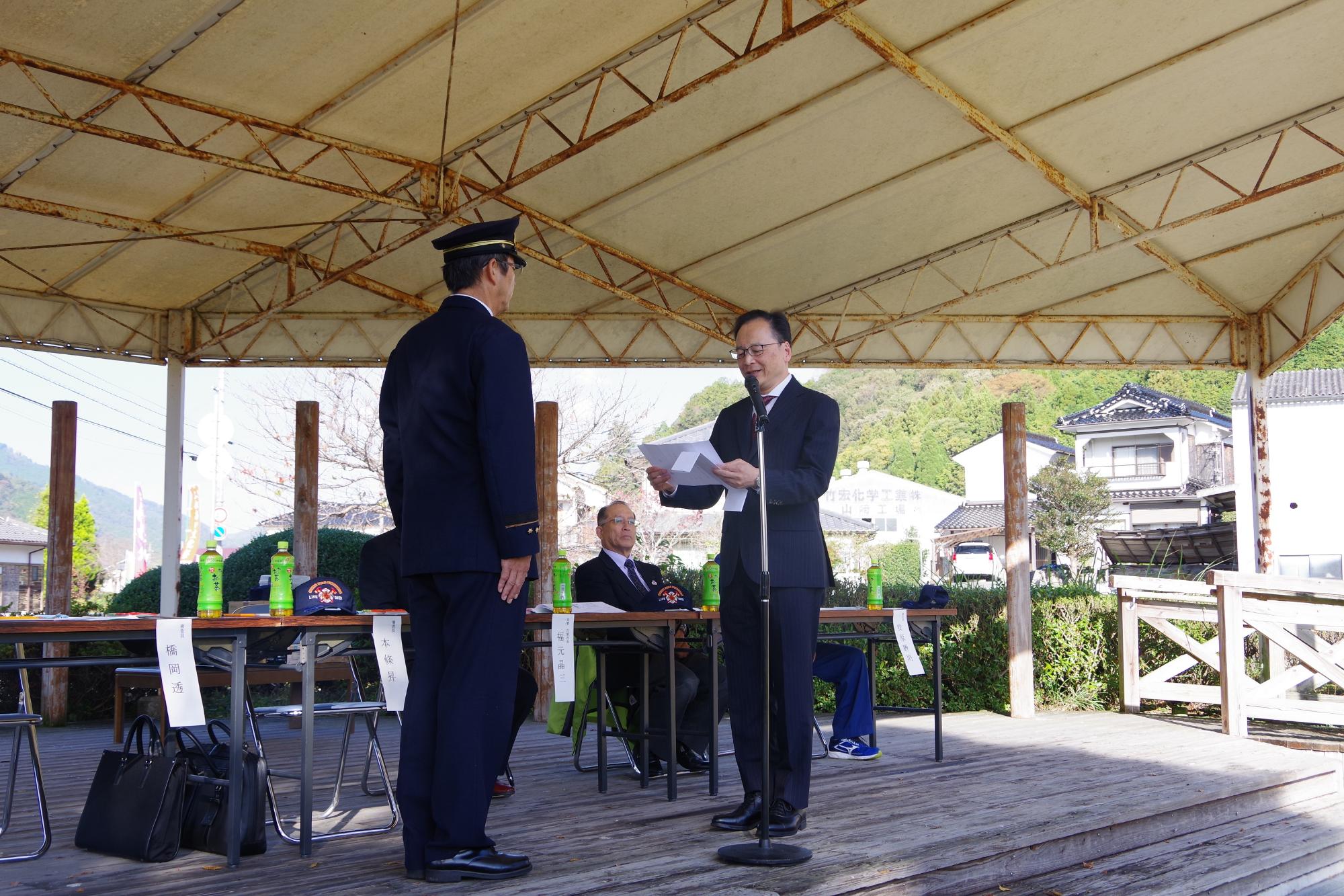 宍粟防火協会会長が宍粟消防署長に向き合い、目録を読んでいる写真