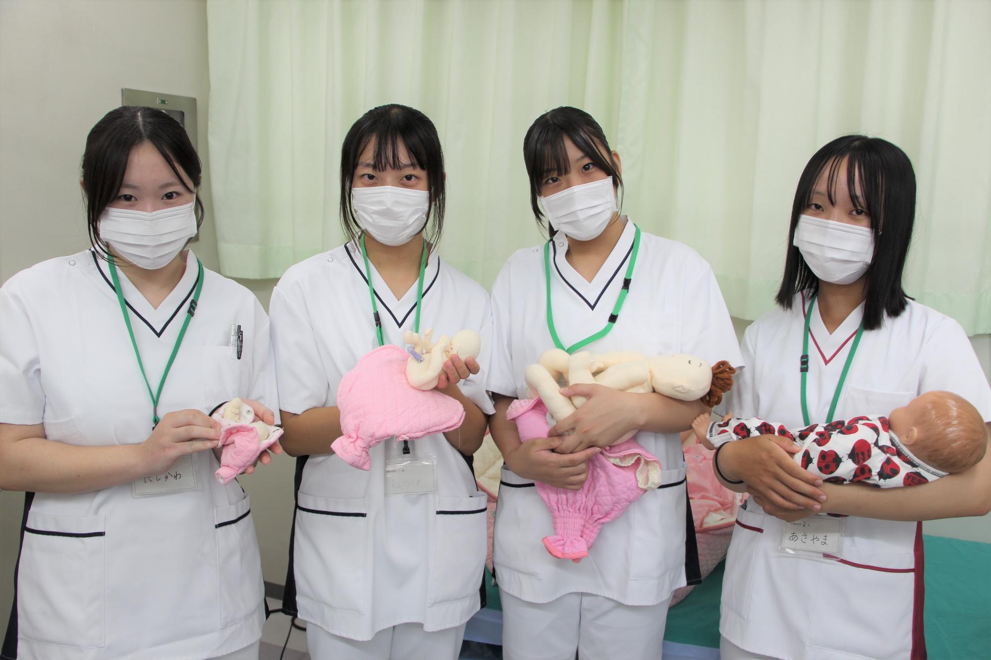山崎高校の生徒4人が赤ちゃんの人形を抱いている様子