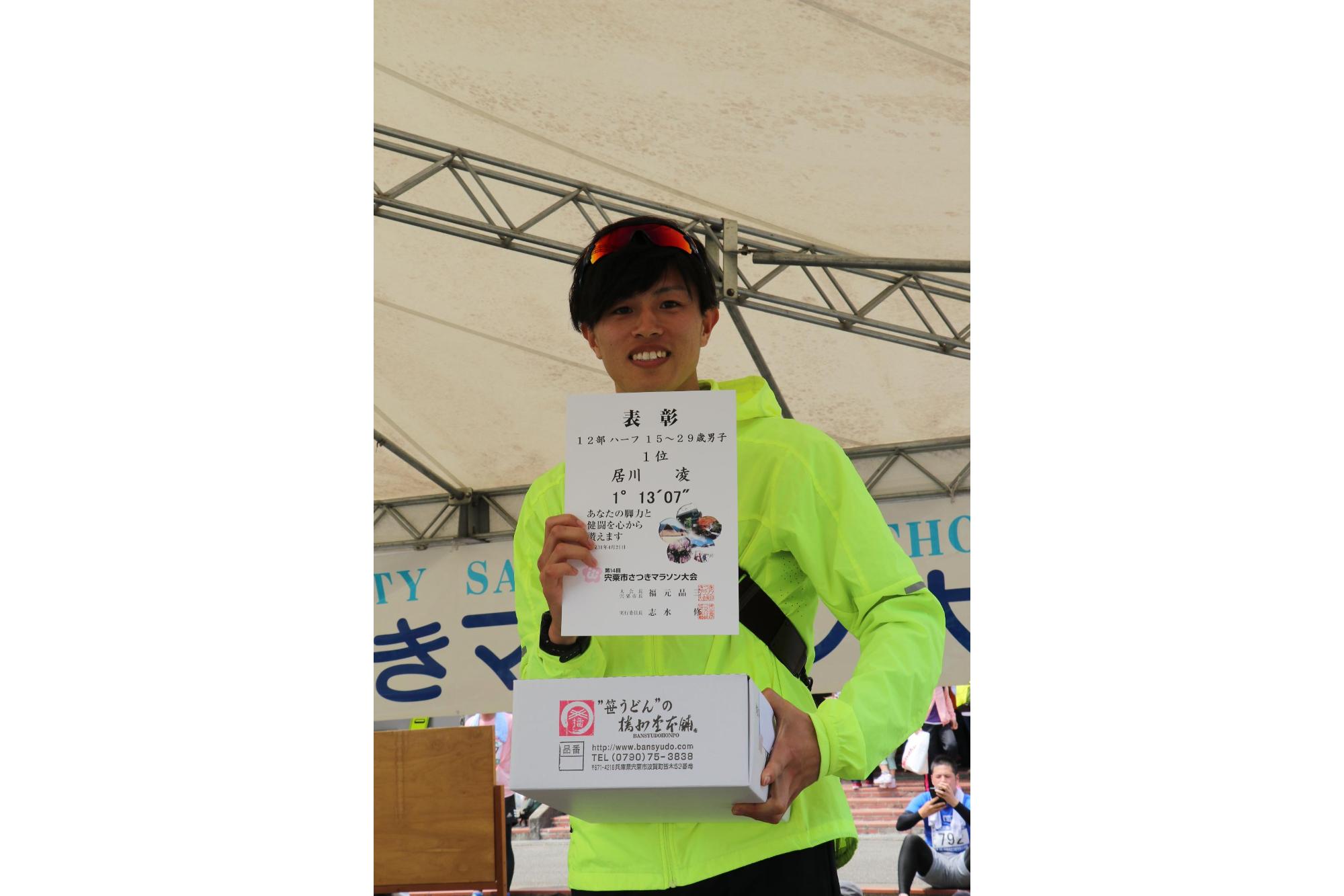 上の写真で力走していた居川さんがハーフの部一位の賞状と景品を手にしている記念写真