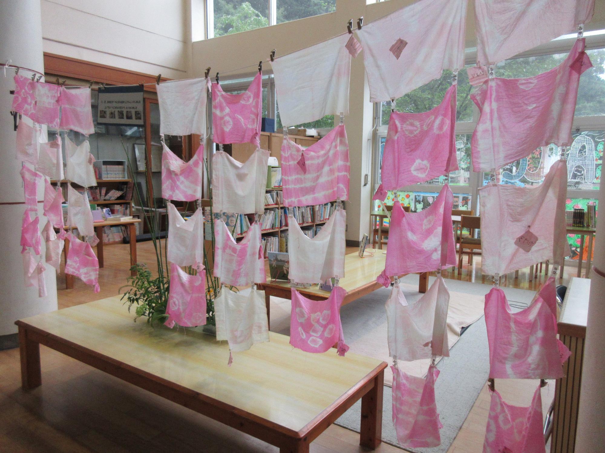 様々な模様のベニバナで染めた布が教室内で壁上に干された写真