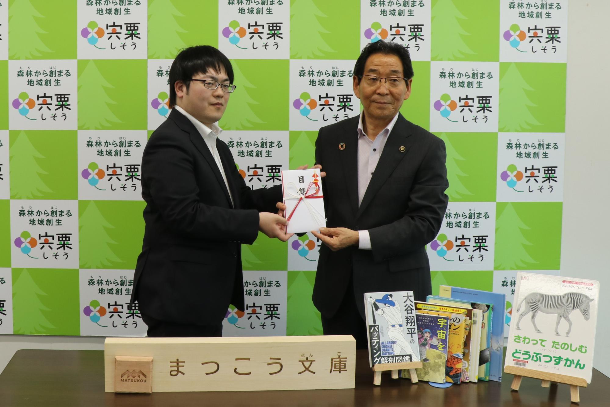 松本さん(左)から目録を受けとる市長(右)