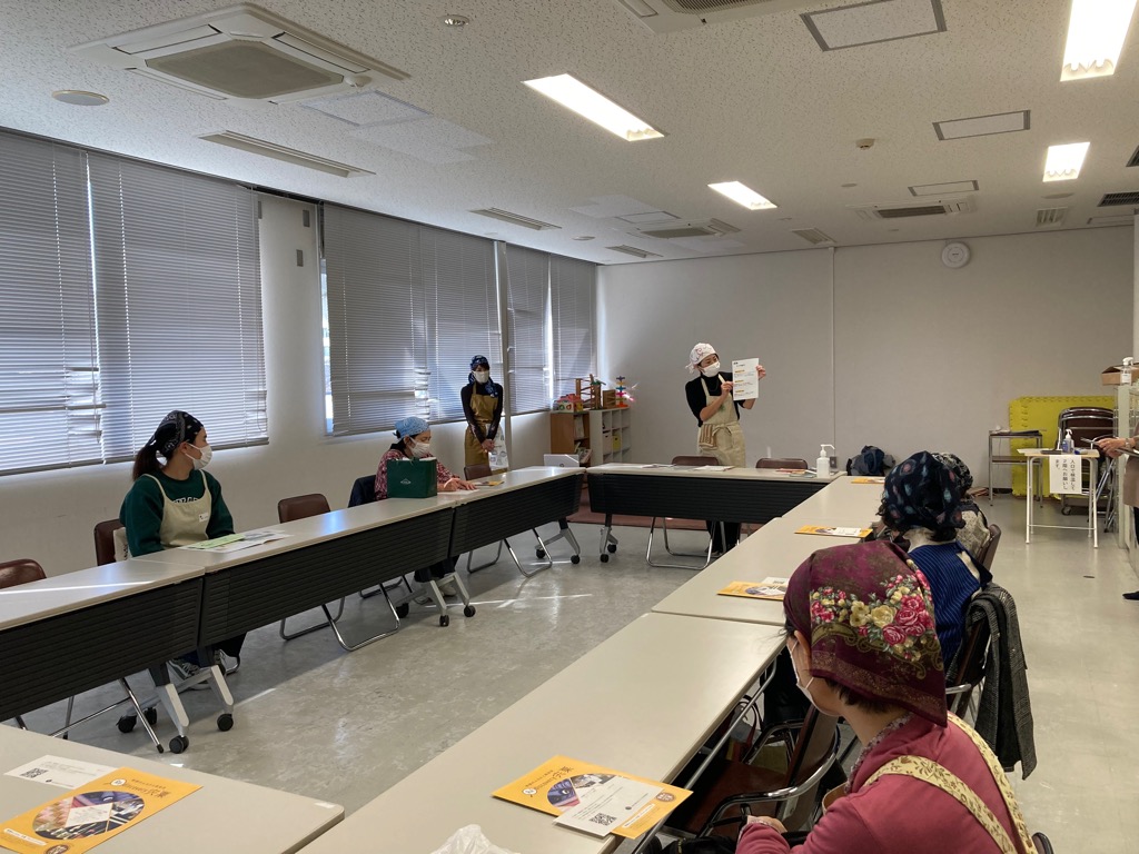 会議テーブルの周囲に参加者が座り、発酵に関する講師からの説明を聞いている写真