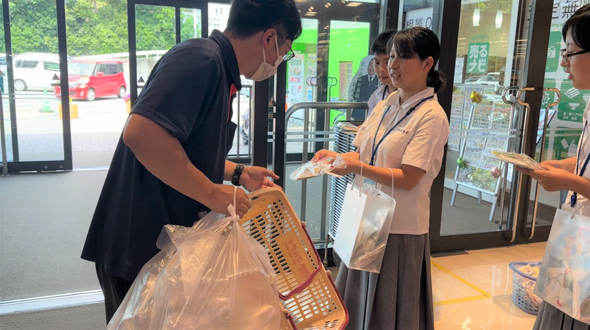 伊和高校の生徒がイオン山崎店を訪れたお客さんに啓発グッズを手渡している様子