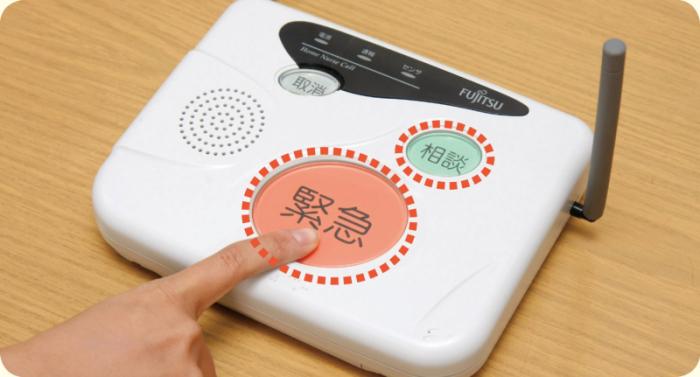 富士通製緊急通報装置の写真。中央に大きな「緊急」ボタン、その右上に「相談」ボタンを配置。