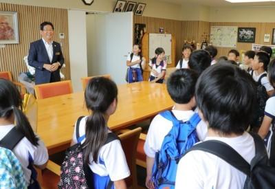 小学生児童たちが市長室の大きな面談用のテーブルを囲み市長から説明を受けている写真
