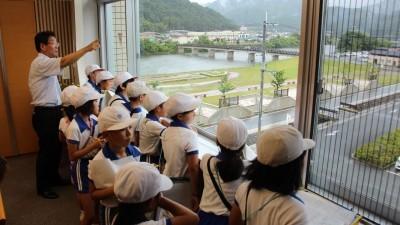市長と白い帽子をかぶる小学生達が市長室のまどからの景色を見ている写真