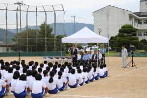 山崎南中スケアードストレイトに参加するグラウンドに体育座りをした生徒達と挨拶をする市長の写真