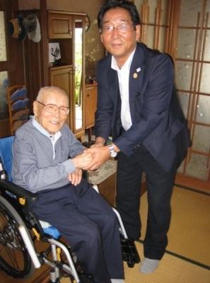 車椅子に座った田路仙之助さんと市長が握手をしている写真