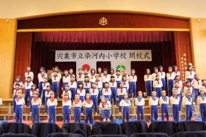 染河内小学校閉校式でステージで合唱する市長の写真