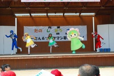 しーたんとソーサマンがステージ上でダンスしているさつき祭りの写真