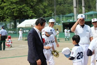 全身白の野球ユニフォームをきた子どもたちに話しかけている市長の写真