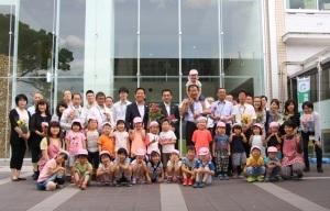 市役所を訪れた園児たちと市役所職員たちが市役所の前でとった記念写真
