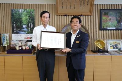 市長室で木藤さんと市長が感謝状を手にしている記念写真