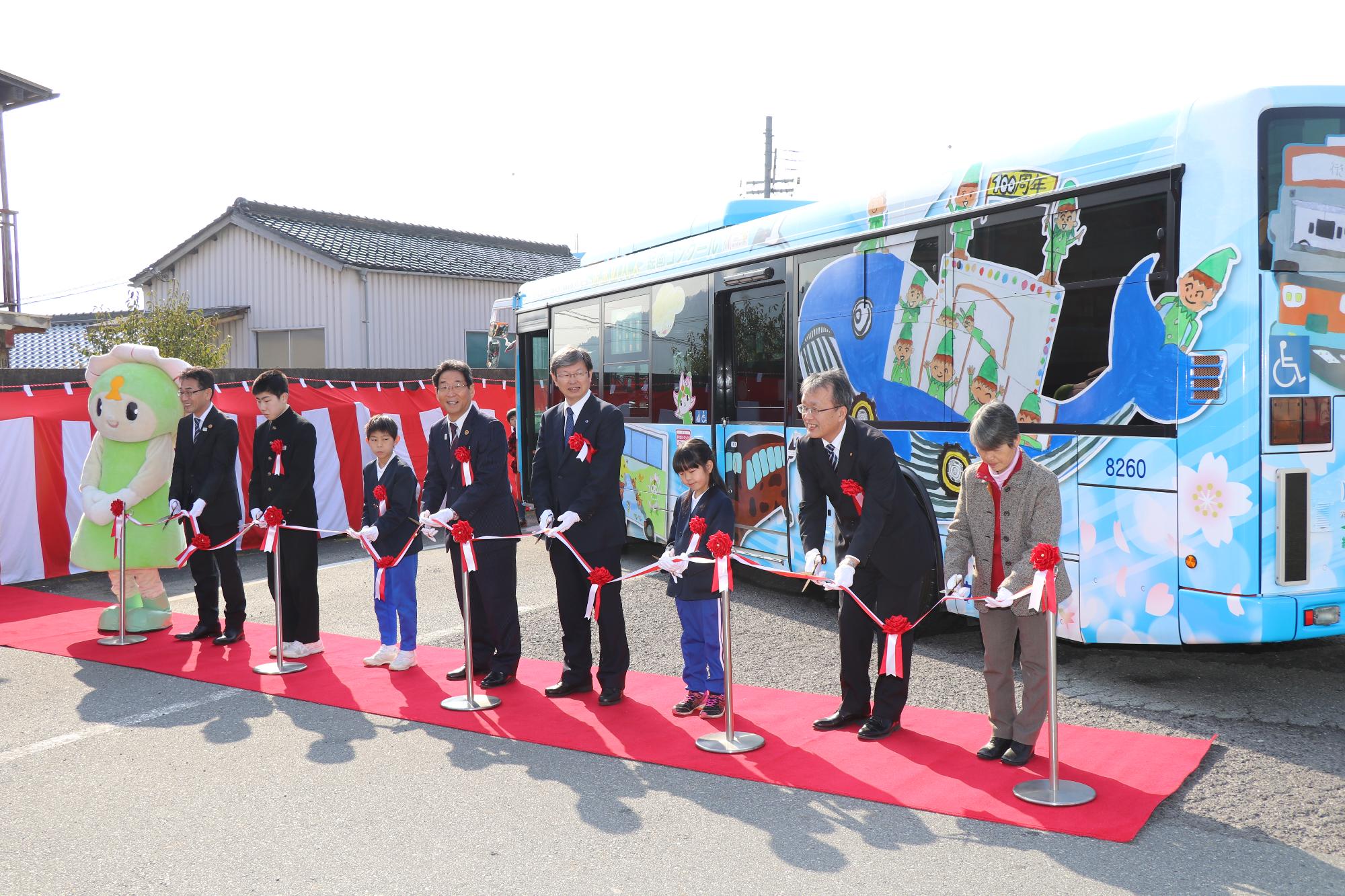 「未来のバス絵画コンクール」の入賞作品がデザインされた記念バス運行開始のテープカットの写真
