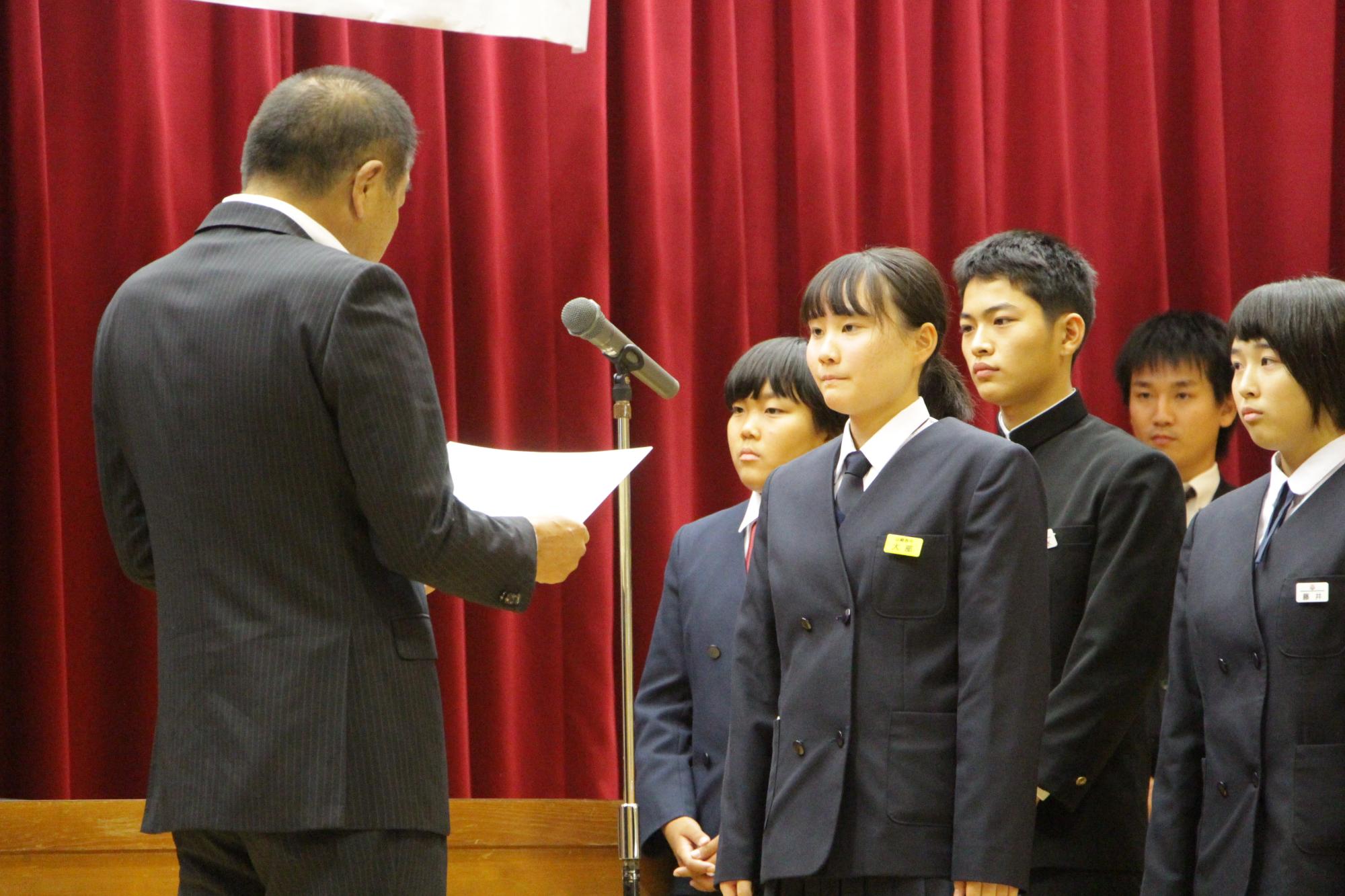 令和元年英語スピーチコンテストで最優秀賞の表彰状を受け取る受賞者の写真