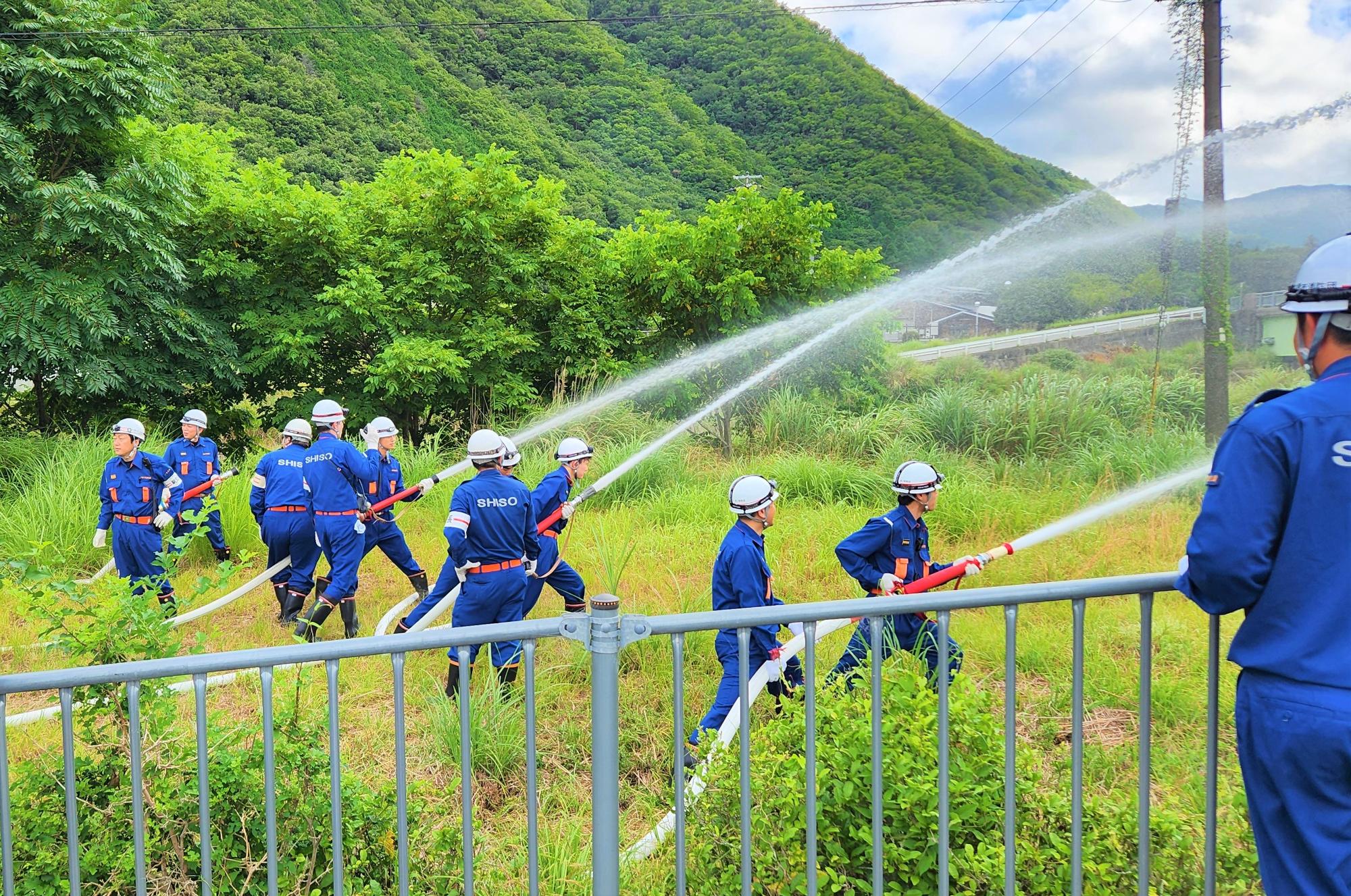 消防団員が空き地に向けて放水する様子