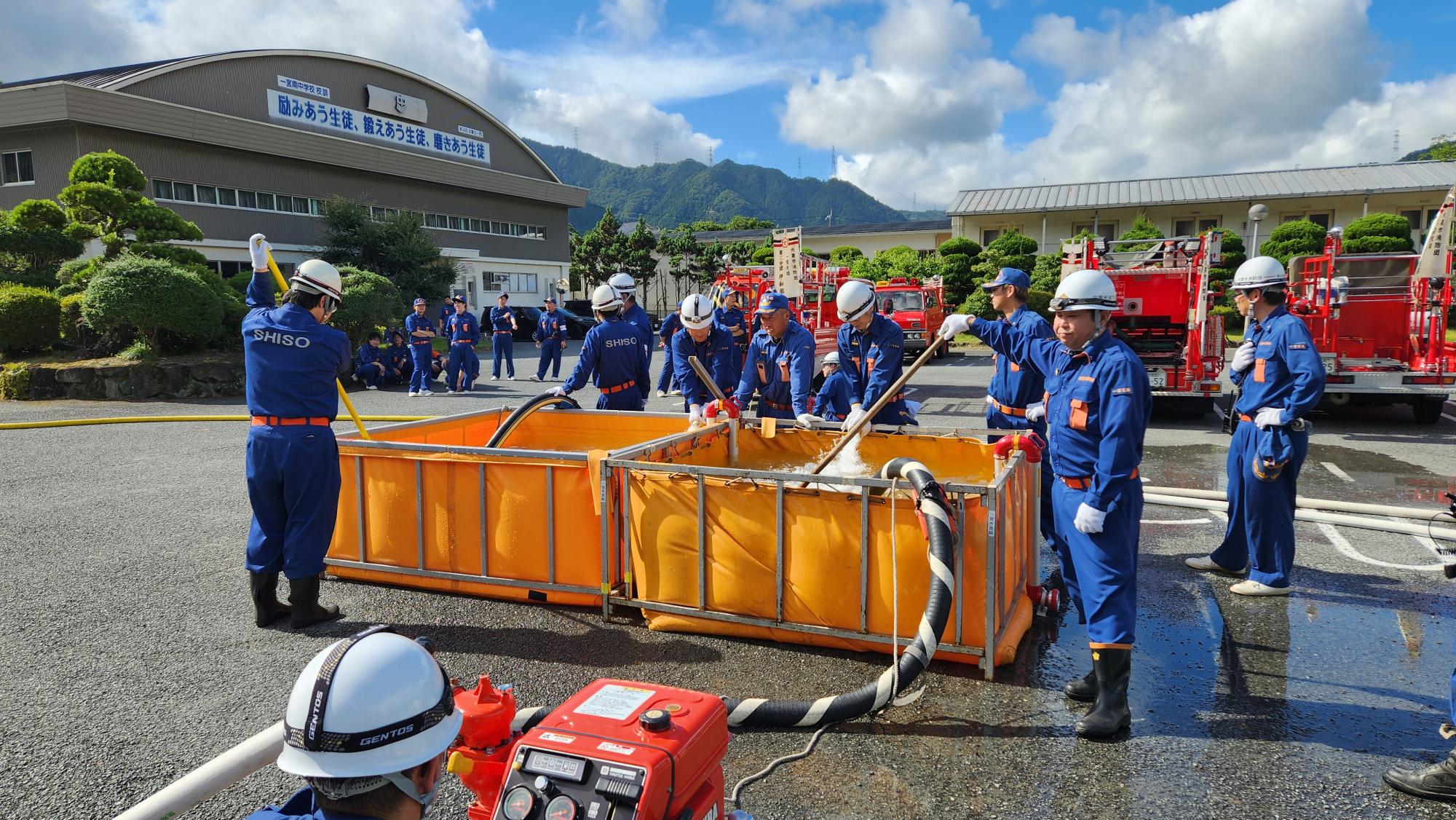 水を貯めた簡易水槽から可搬ポンプで水を吸い上げ、無線で連絡しながら水の吸い上げ量、供給量を調整している様子
