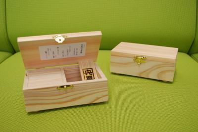 黄緑のソファの上に枯れた木製の蓋が開いた状態と閉じた状態の2つの宍粟市字書き歌オルゴール