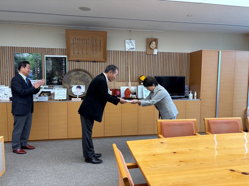 人権擁護委員の退任式で退任する委員が記念品を受け取っている写真