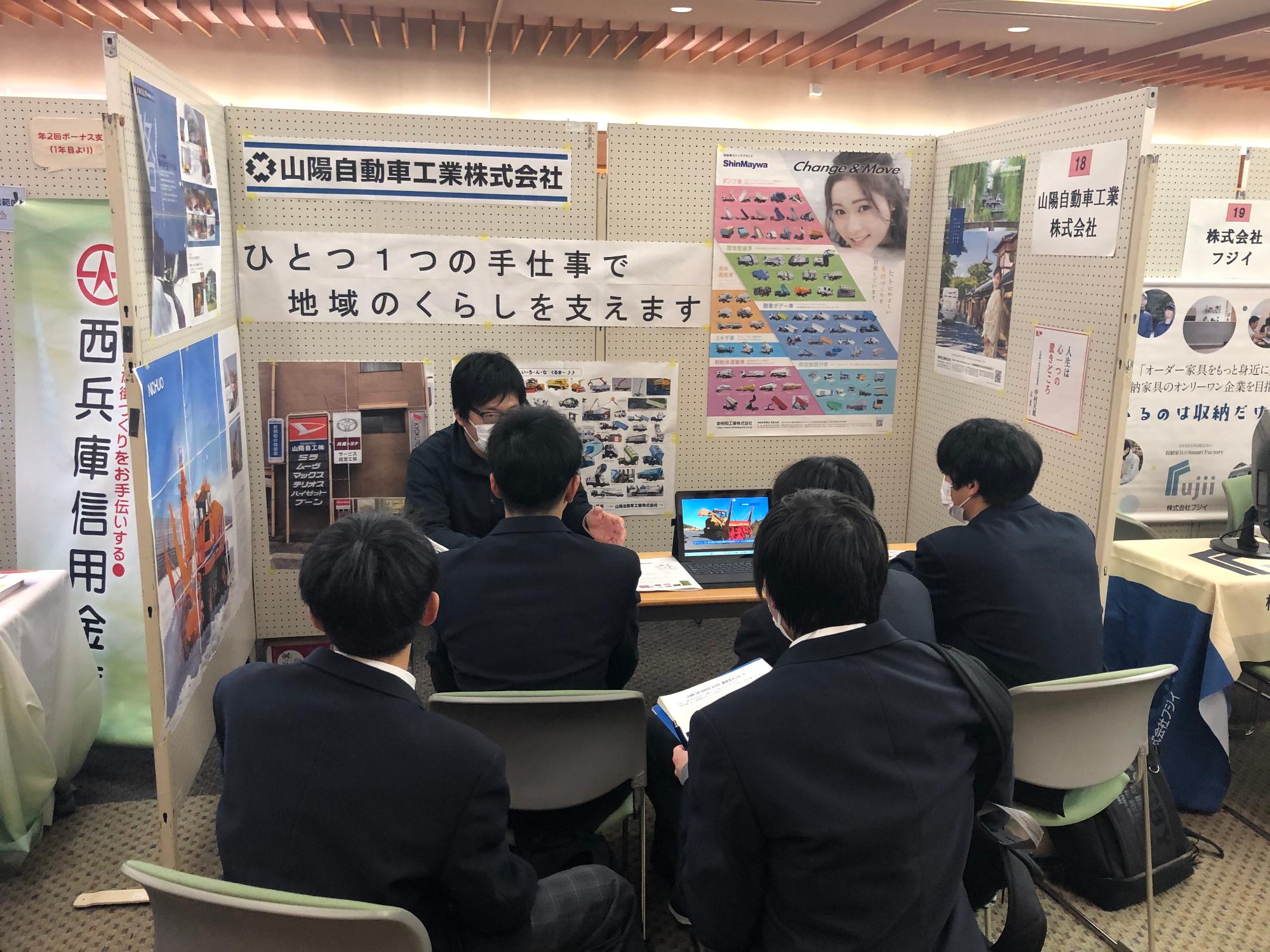参加者が企業の担当者から説明を受ける様子の写真