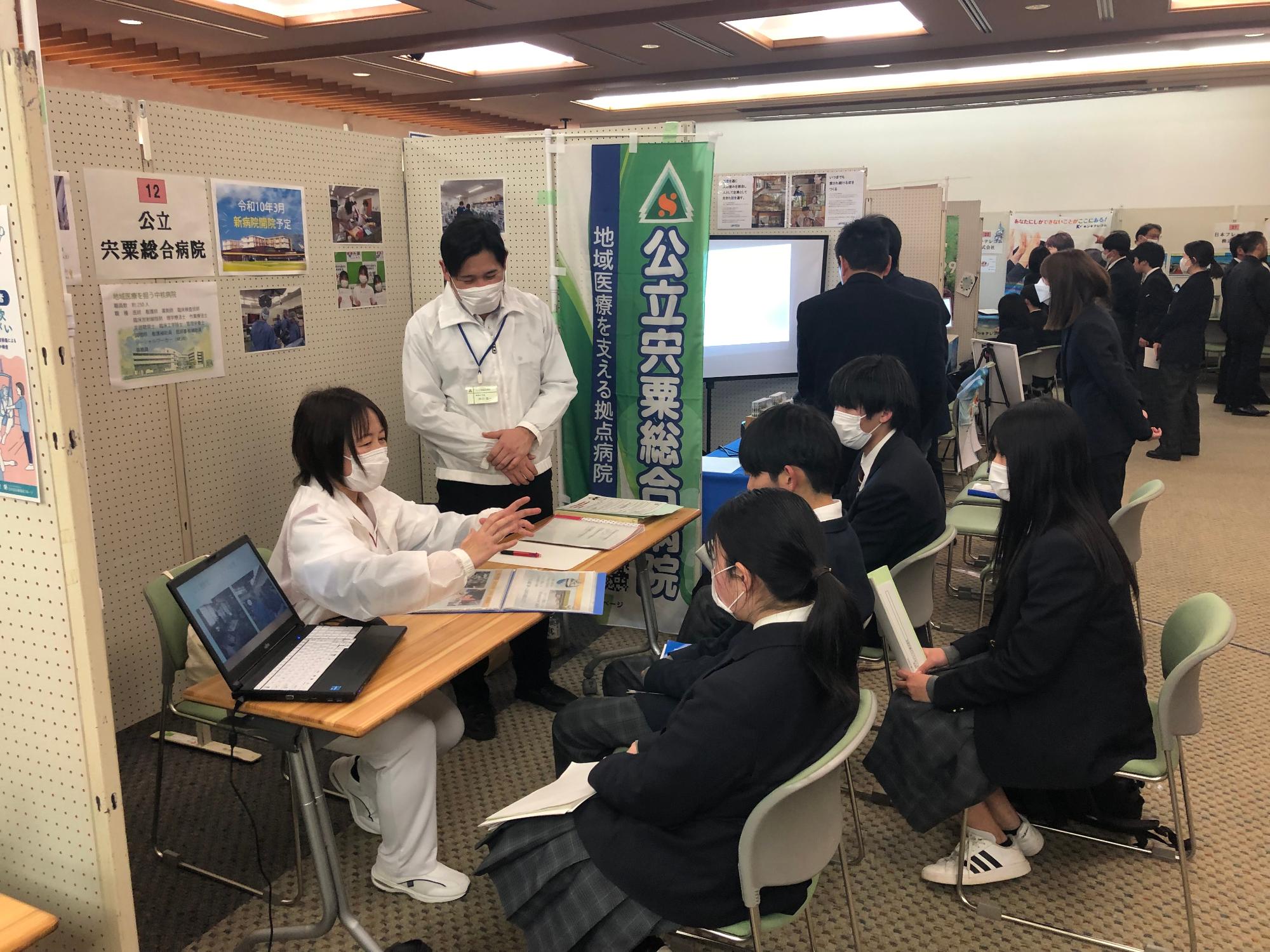 参加者が企業の担当者から説明を受ける様子の写真