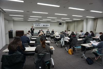 会議室で議員が大勢の市民へ活動の報告をしている写真