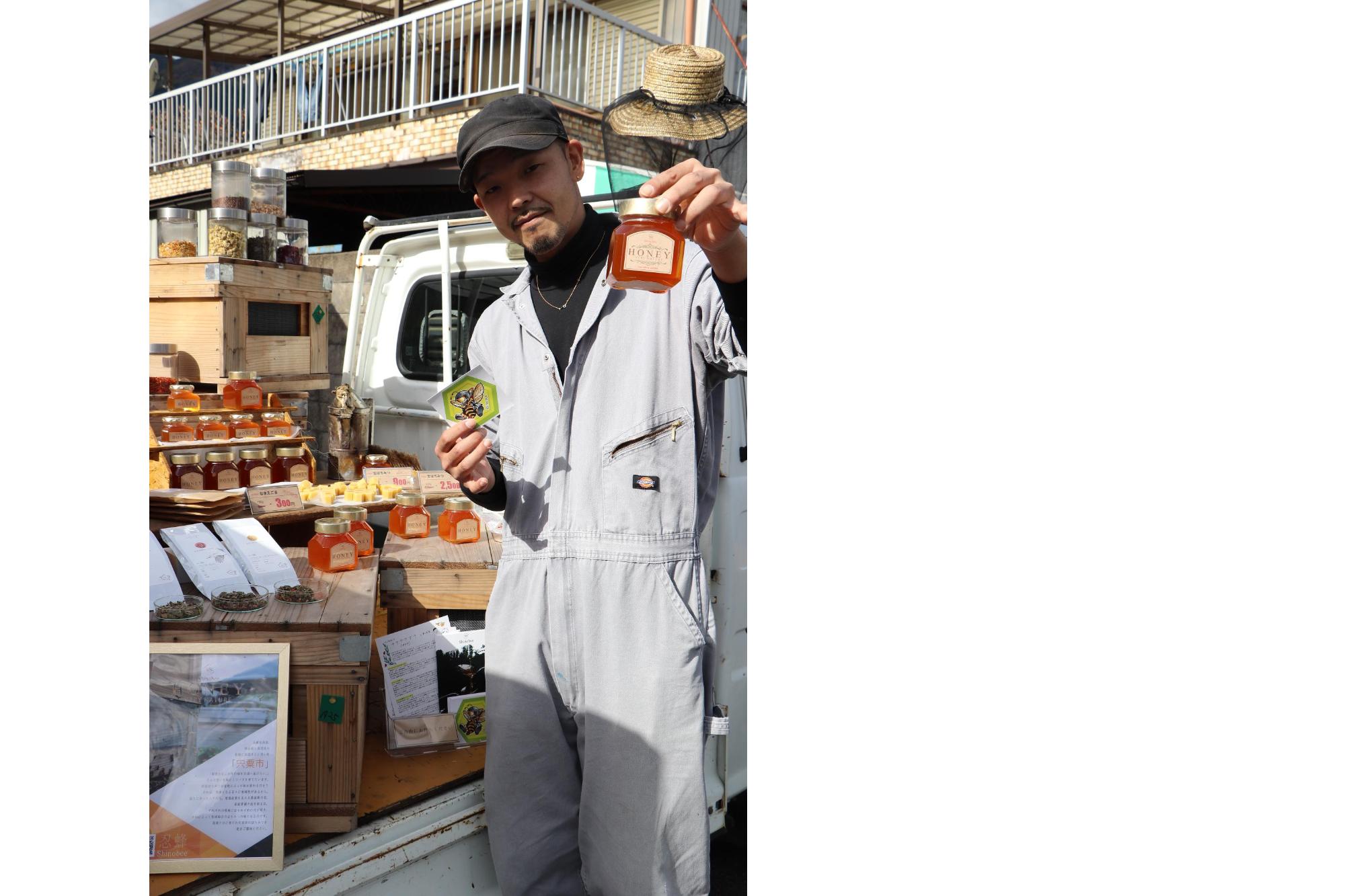 地域おこし協力隊の田中さんが商品のハチミツをPRする写真
