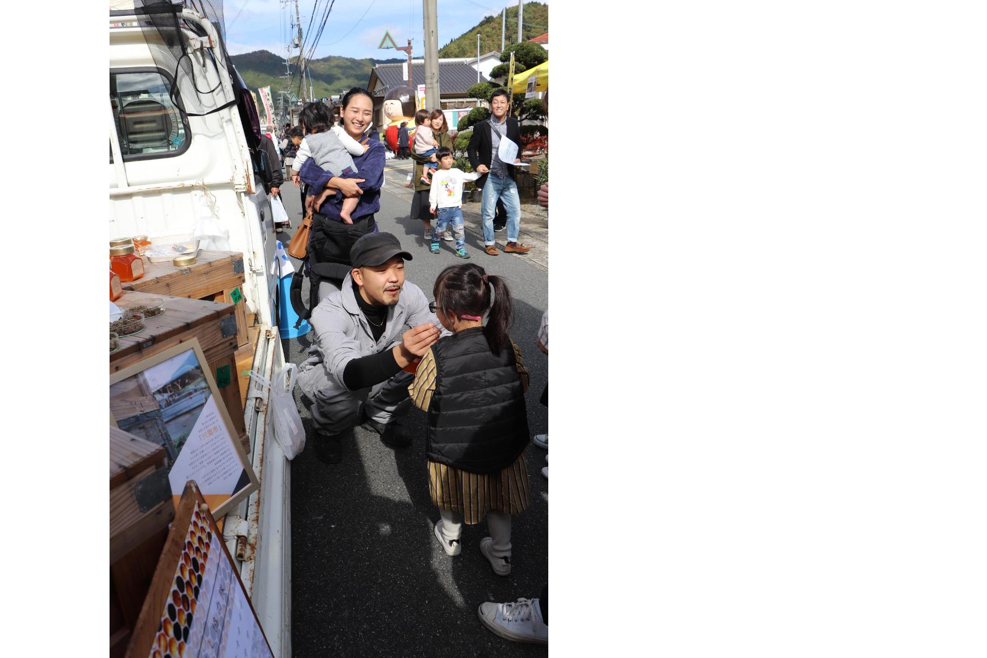 地域おこし協力隊の田中さんが子どもにはちみつを提供している写真