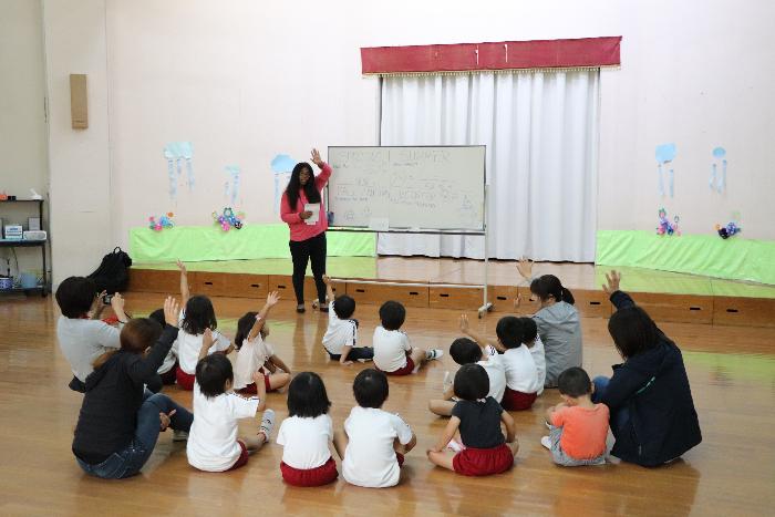 ホワイトボードの前で授業をるジャーマニー先生と授業を受ける園児達の写真