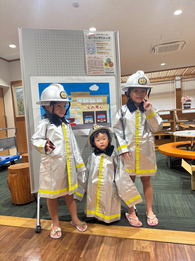 子供たちが消防士の服を着て記念撮影をする様子