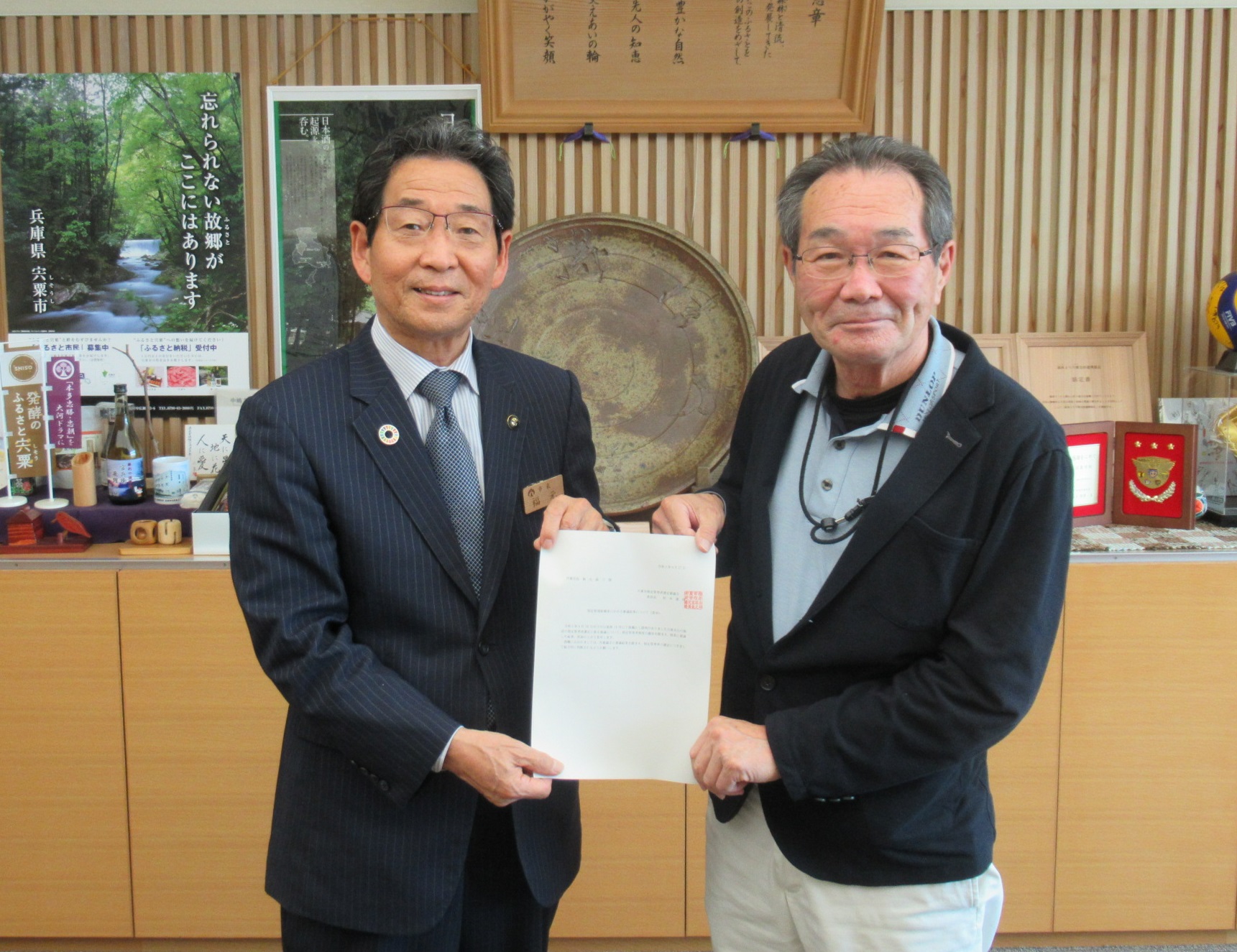 審議会から提出された答申書を福元市長と審議会の杉本委員長が手に持って掲げている写真