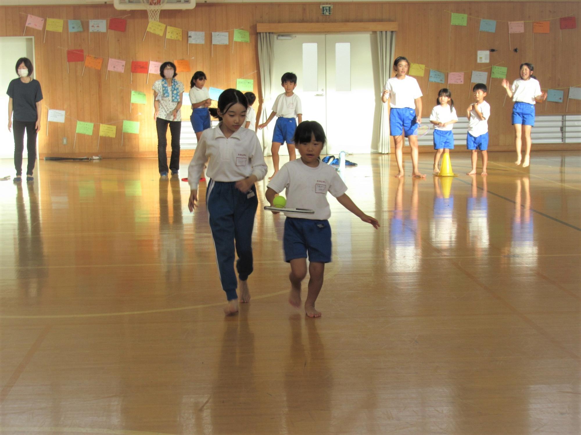 参加者が手に持ったラケットの上にテニスボールを乗せて、落とさないように気を付けながら競争している写真