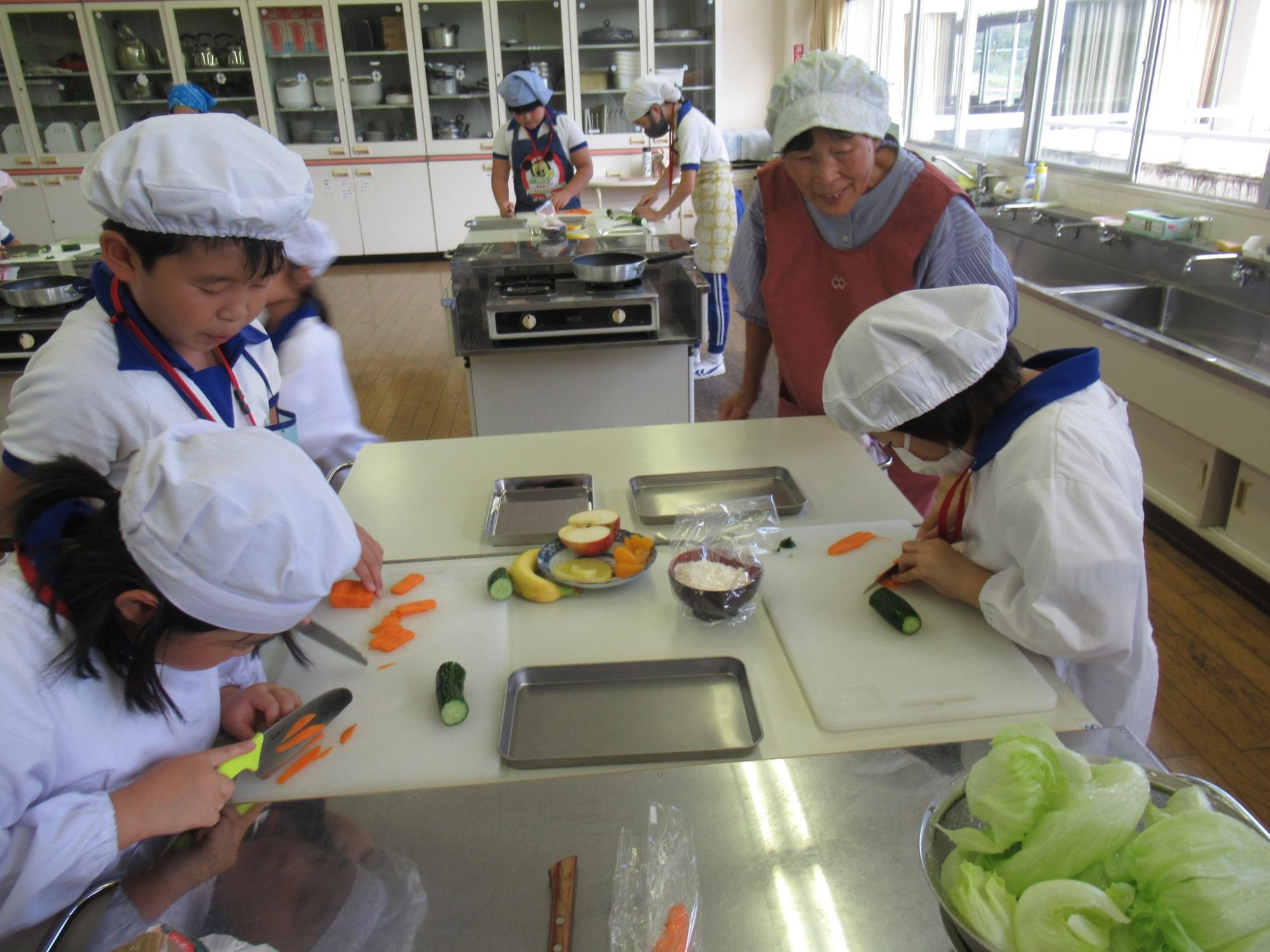 参加者がニンジンやキュウリなど野菜をカットしている写真