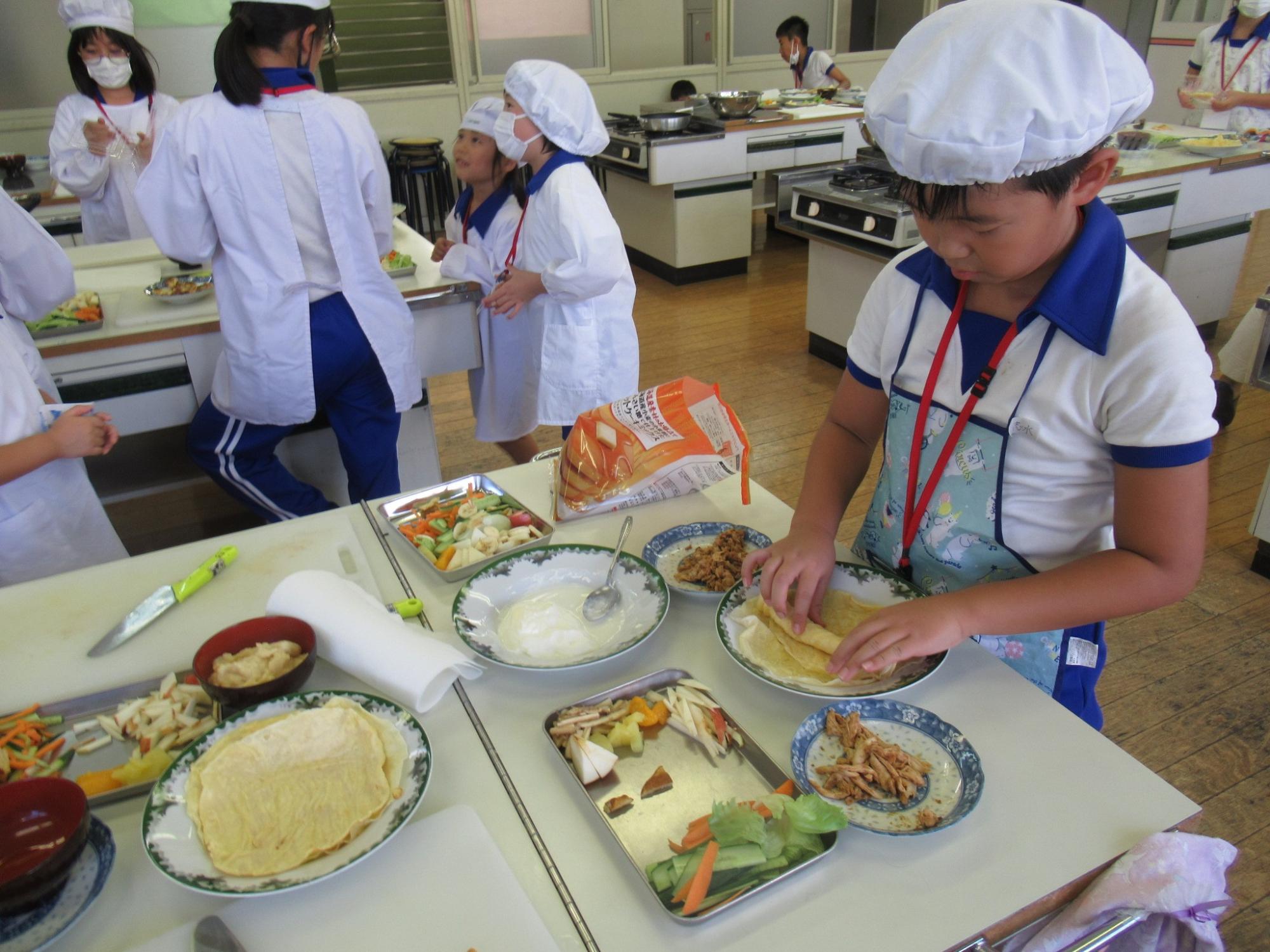 参加者がお皿の上に広げたクレープの生地を巻いている写真