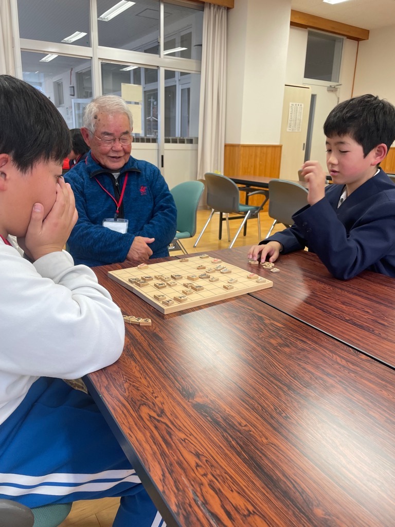 参加者が将棋の駒を手にもって、次の一手をどう打つか考えている写真