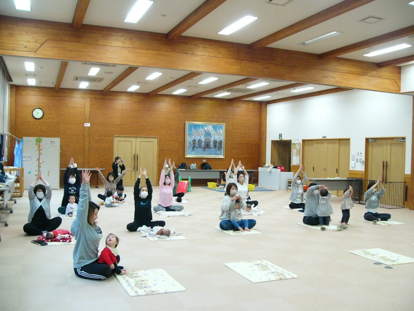 学遊館ホールで体操する親子連れの写真