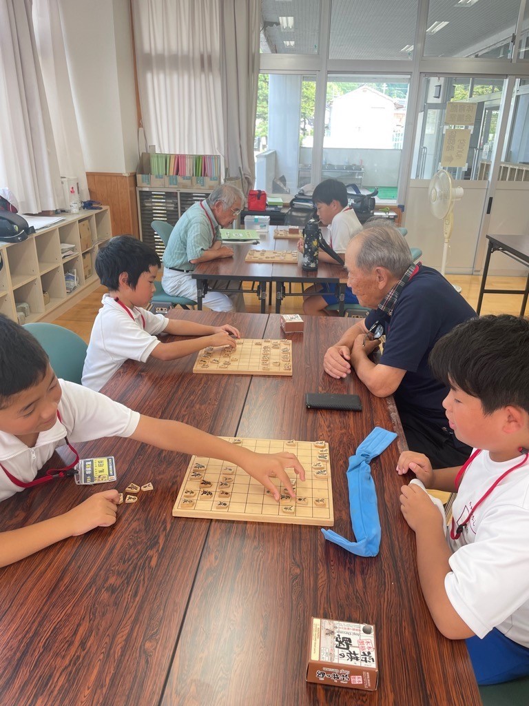 参加者や指導者が向かい合って将棋の対局をしている写真