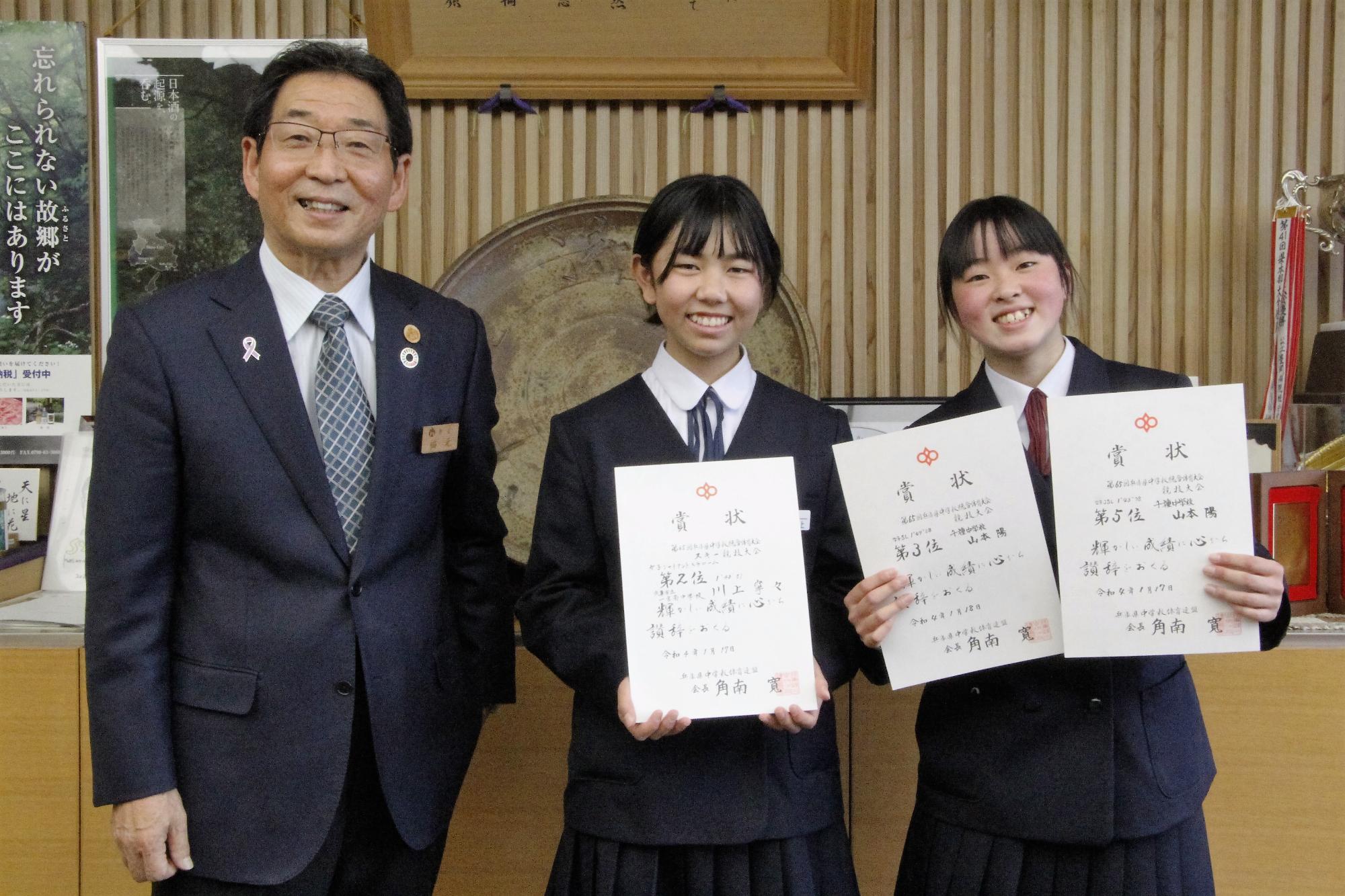 アルペン競技で全国大会に出場する一宮南中学校の川上寧々さんと千種中学校の山本陽さんが賞状を手に笑顔で宍粟市長と並んでいる写真