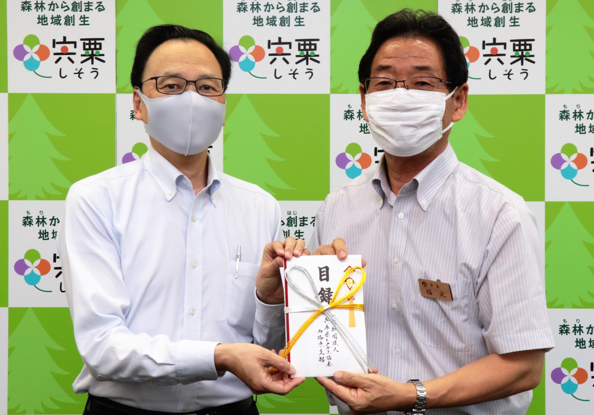 寄付金目録を手に左はLPガス協会西播東支部様、右は福元市長が並んでいる写真