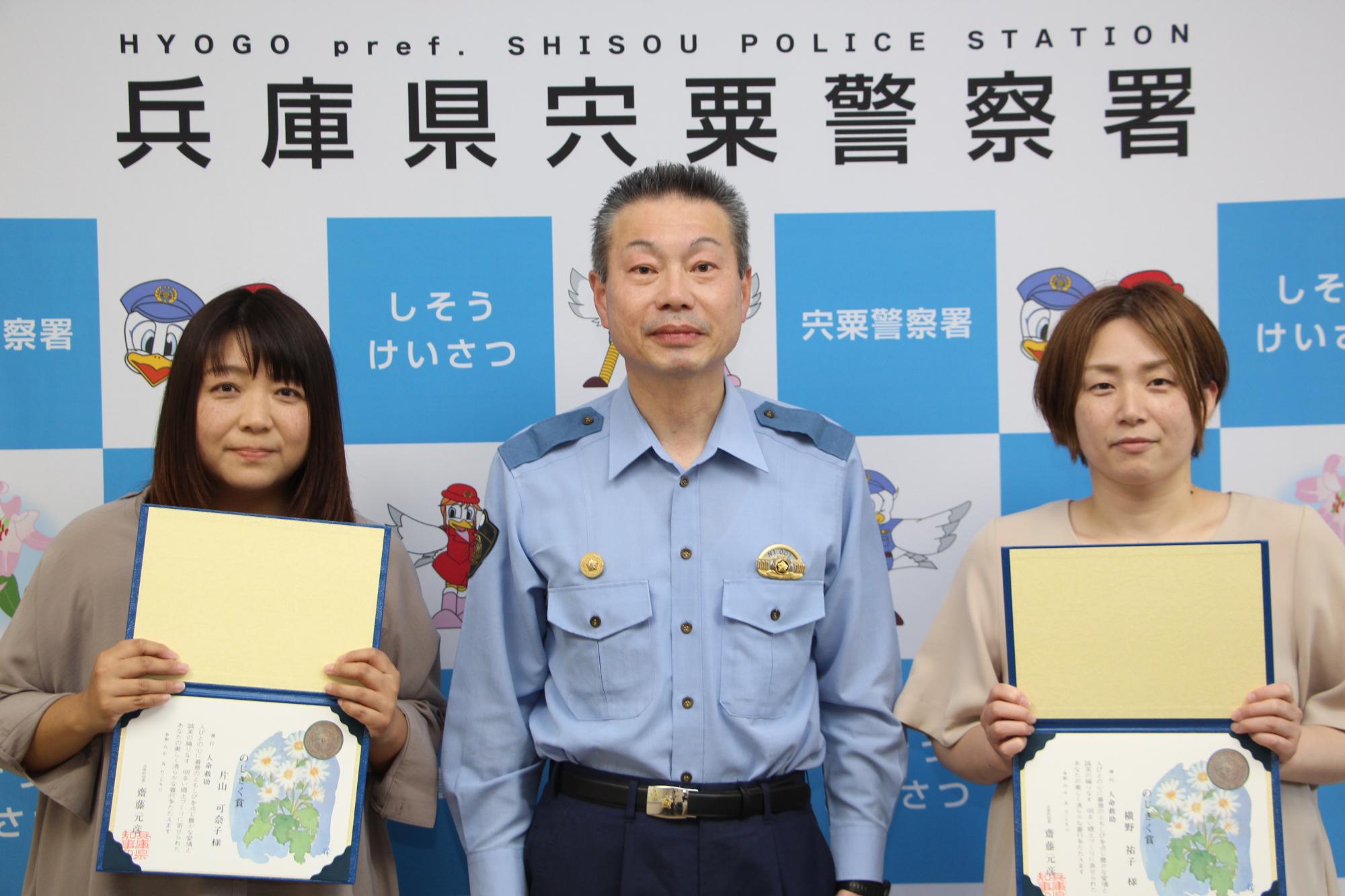 のじぎく賞が贈られた保育士2人と賞状を手渡した宍粟警察署長が並んで立っている写真