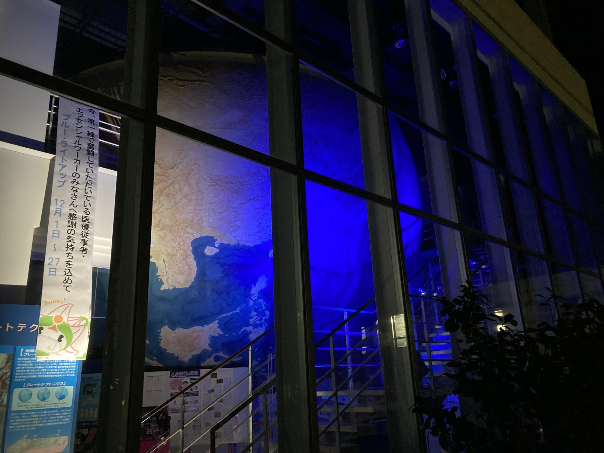 地球の模型が青くライトアップされている防災センターを外観から見た写真