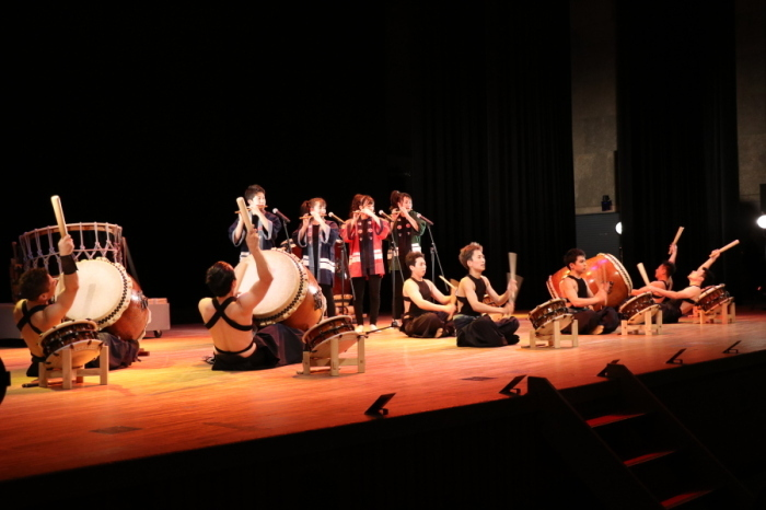 ステージで和太鼓と笛を演奏する演者たちの写真