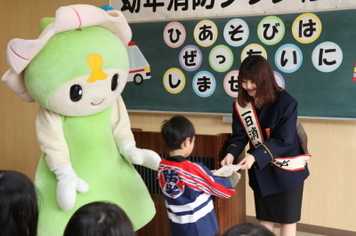一日消防署長に任命された光岡穂乃花さんが幼稚園や保育所の子どもたちに幼年消防クラブ修了証書を授与している写真